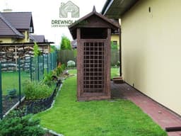 pergola stojąca na trawie przy domu